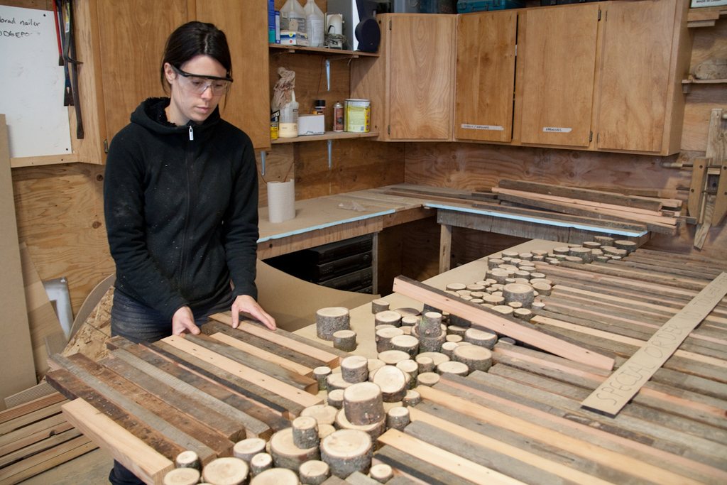 Craftsperson sorting cut wooden pieces on a workbench in a busy workshop