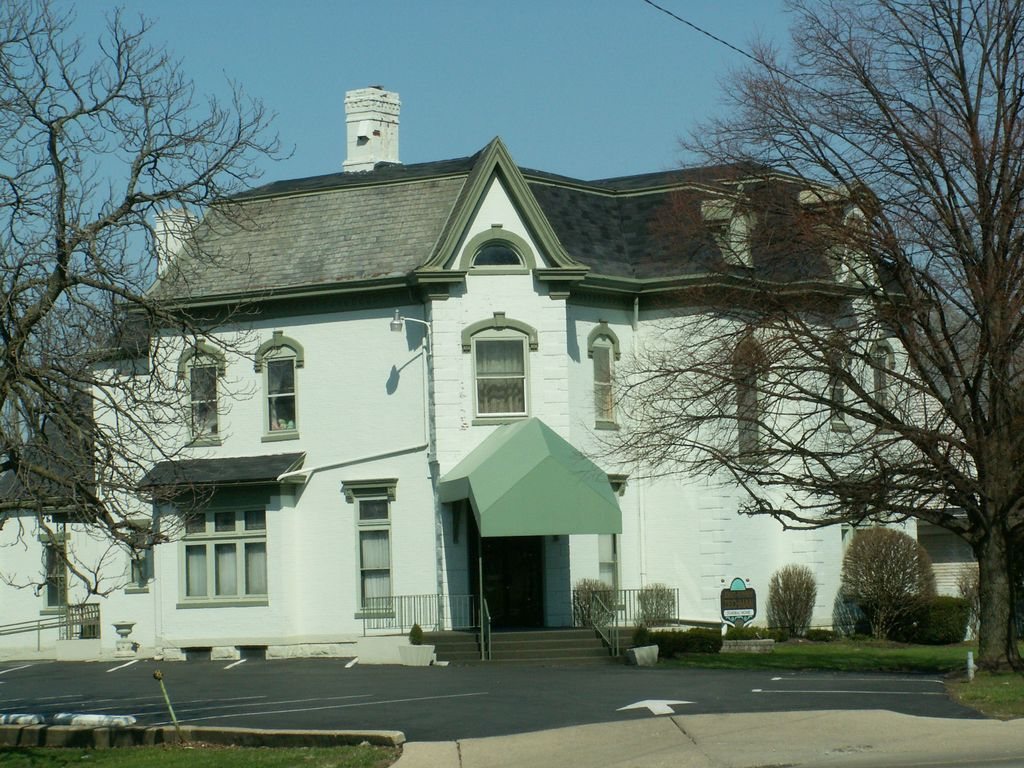 White two storey house with tall windows and a green entrance awning