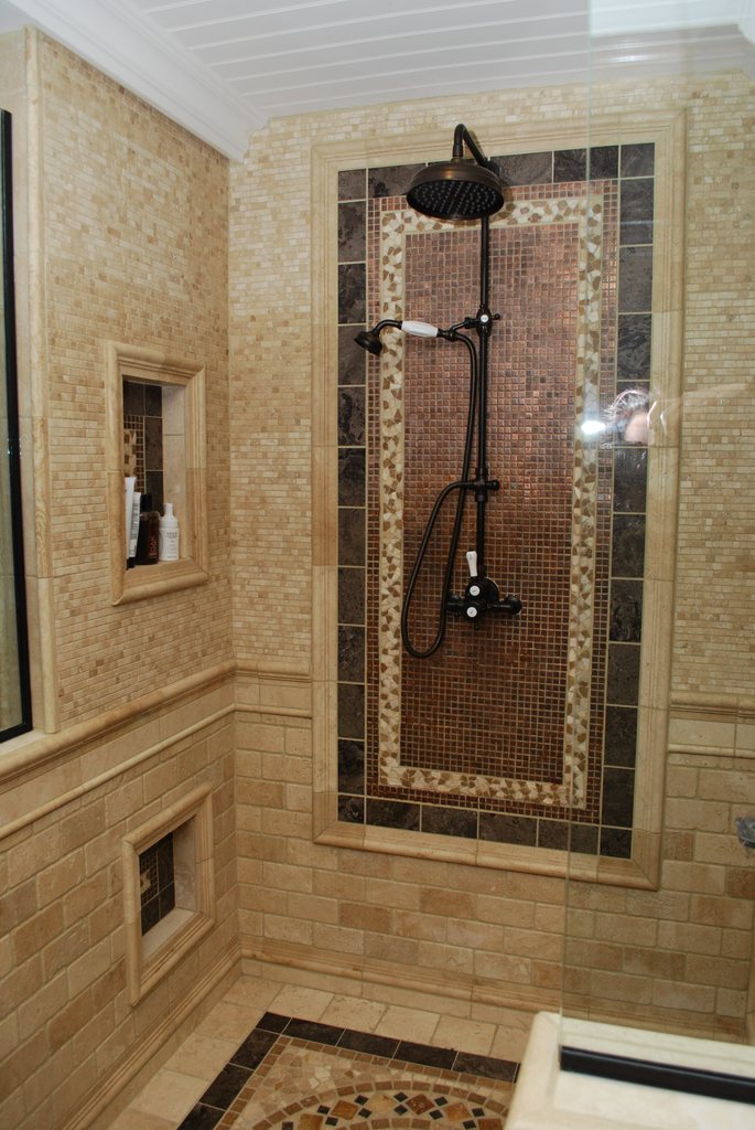 Walk in shower lined with honey coloured mosaic tile and a rain shower head