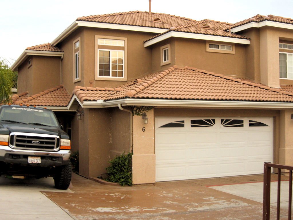 Two storey stucco home with a tiled roof and a wide double garage door