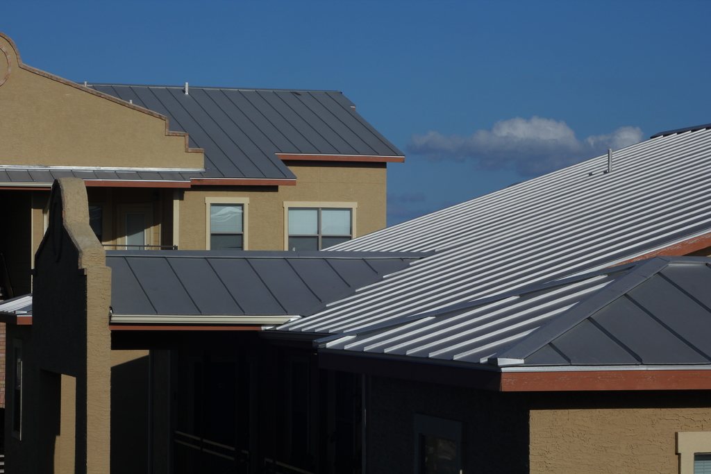 Modern standing seam metal roofs on neighbouring homes under a blue sky